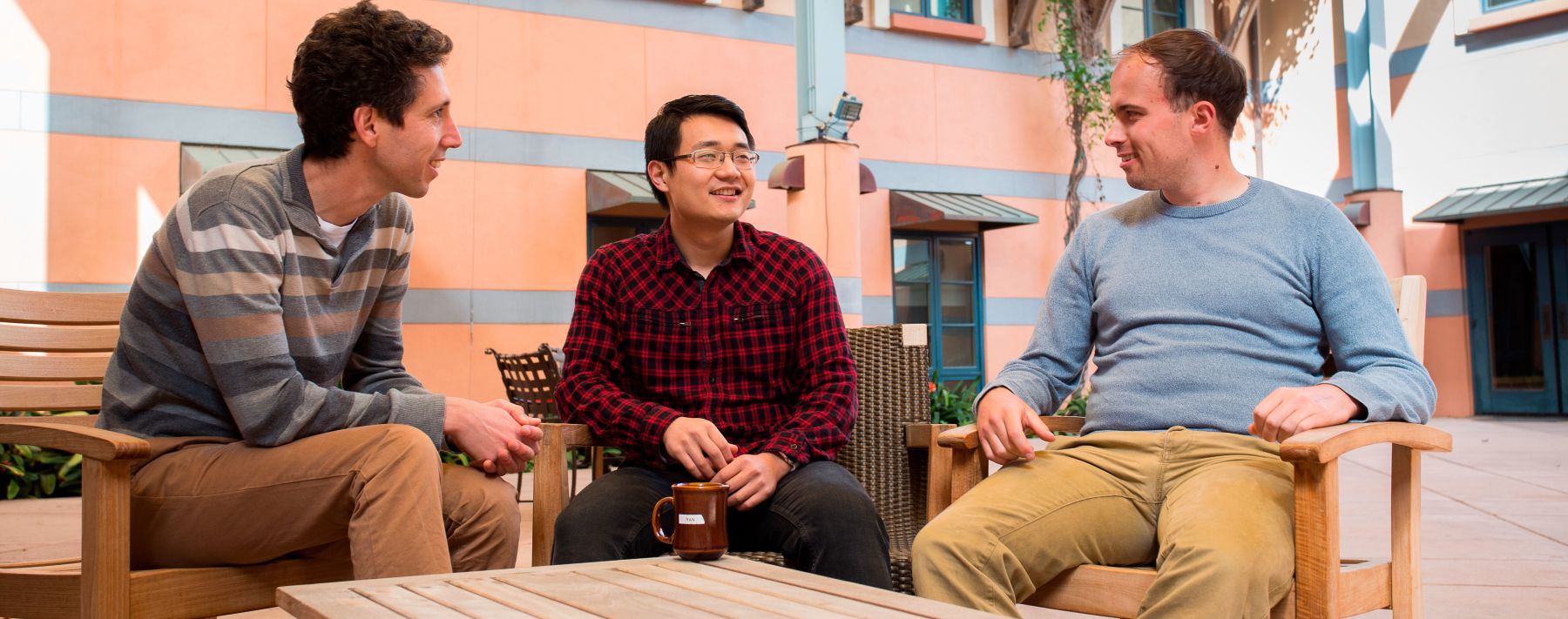 Photo of three physicists talking in a courtyard